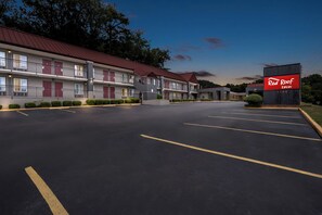 A Red Roof Inn with a two-story building, a parking lot, and a well-maintained lawn.