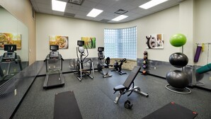 Un gimnasio con cintas de correr, elípticas y pelotas de ejercicio.