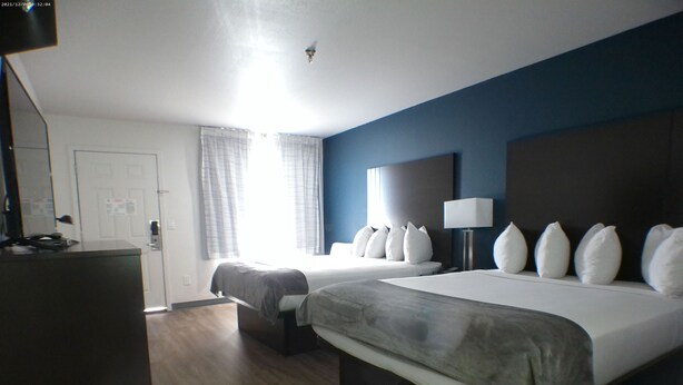 A hotel room with two beds, a desk, a lamp, and a view of the outside. - Greentree Inn Holbrook (Holbrook)