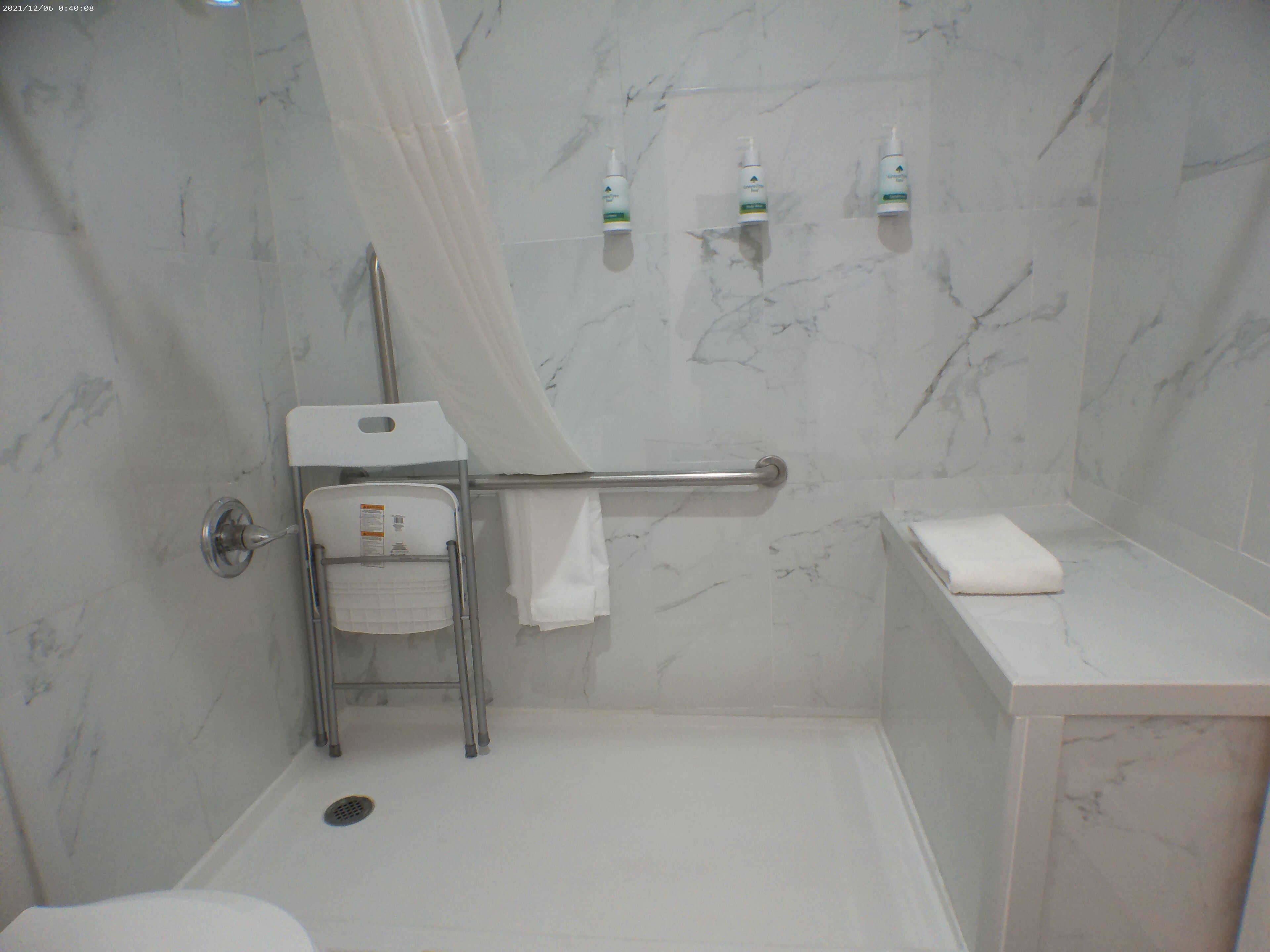 A bathroom with a shower, a toilet, a sink, and two bottles of shampoo on the wall.