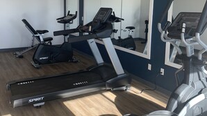 A gym with treadmills, an elliptical, and a bench press. - Greentree Inn Holbrook (Holbrook)