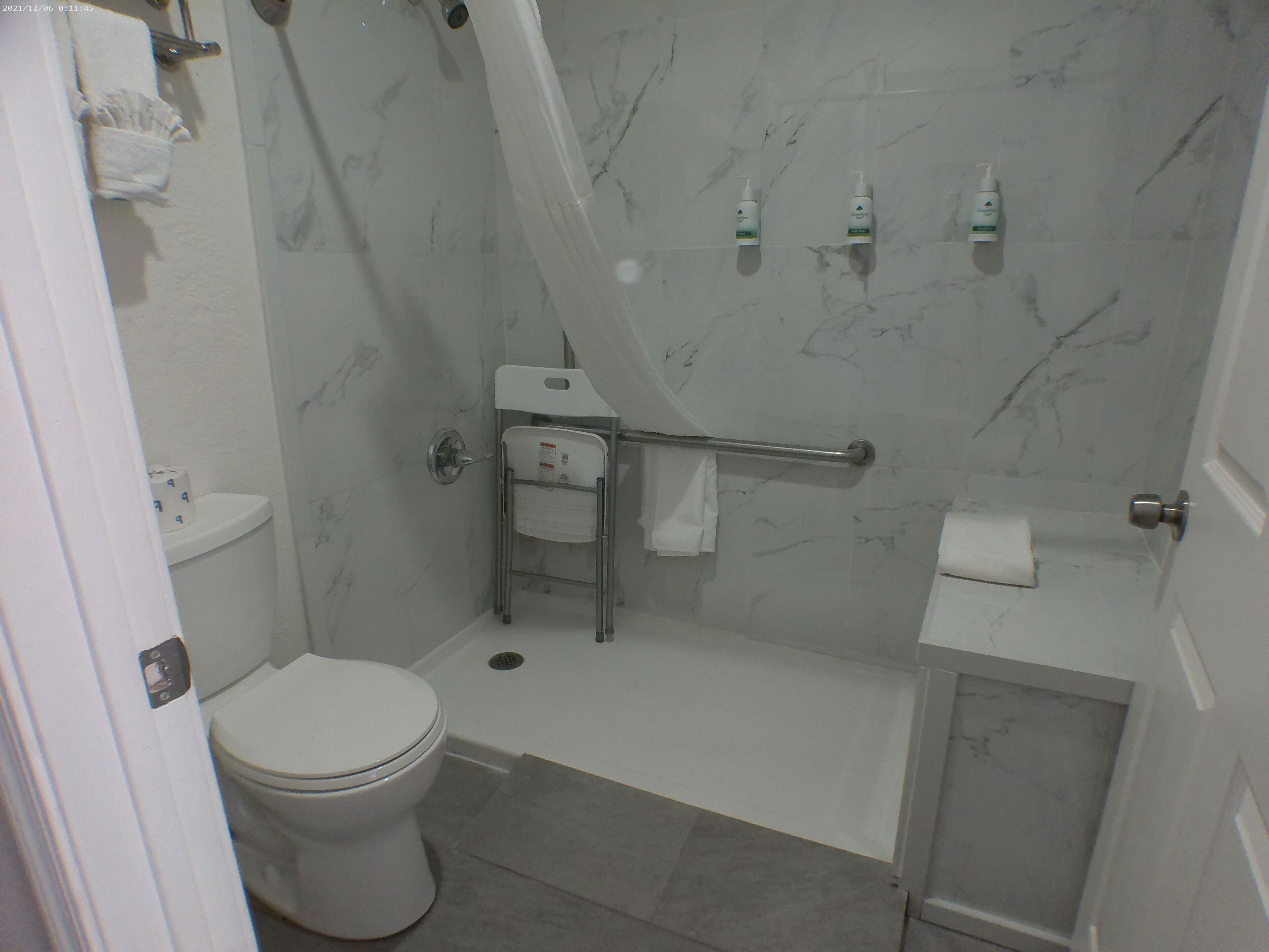 A bathroom with a toilet, a shower with a glass door, a sink, and a towel rack.