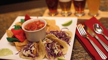 Un plato de tacos con salsa y lima, acompañado de una servilleta roja y cubiertos.