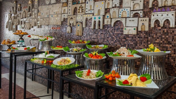 Un bufé con diversos platos y una pared decorativa con diseños arquitectónicos.