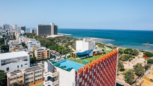 Un hotel de gran altura con piscina en la azotea, vistas al océano y zona de playa.
