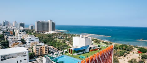 A high-rise hotel with a rooftop pool, ocean views, and a beach area.