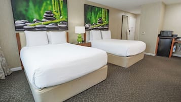 A hotel room with two beds, a desk with a microwave, and a door.