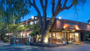 A Creekside Inn lobby with a wooden facade, large windows, and a well-lit entrance. - Creekside Inn (Palo Alto)