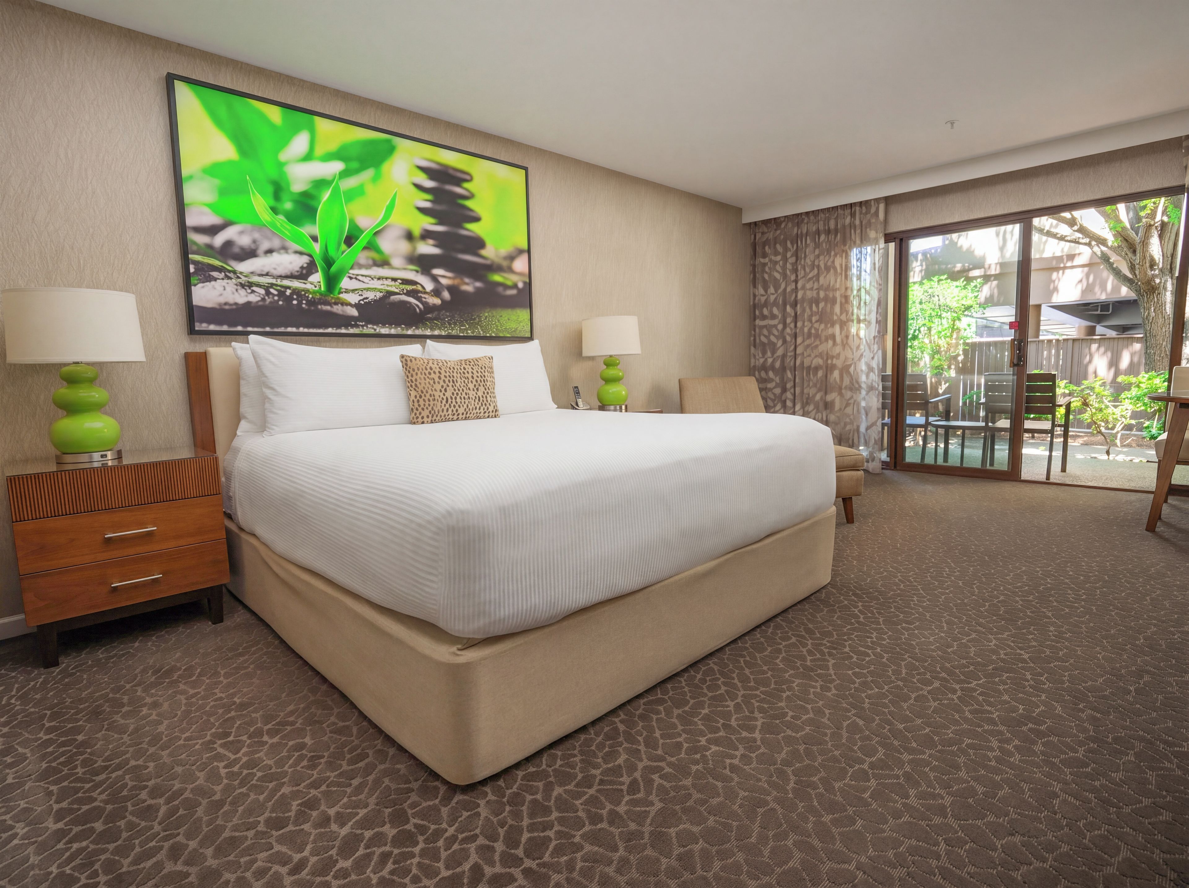 A hotel room with a large bed, two bedside tables, a window with curtains, and a view of the outdoors.