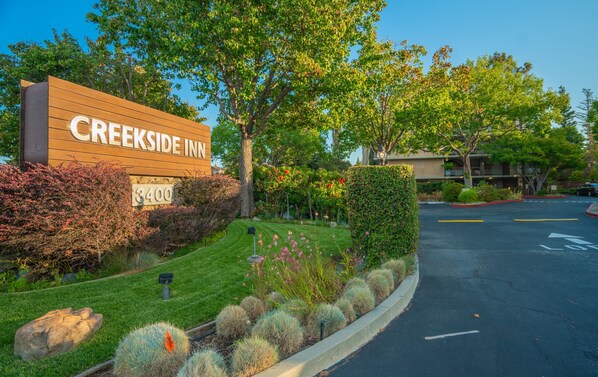 A sign for Creekside Inn with a number 3400, surrounded by landscaped greenery and a parking area.