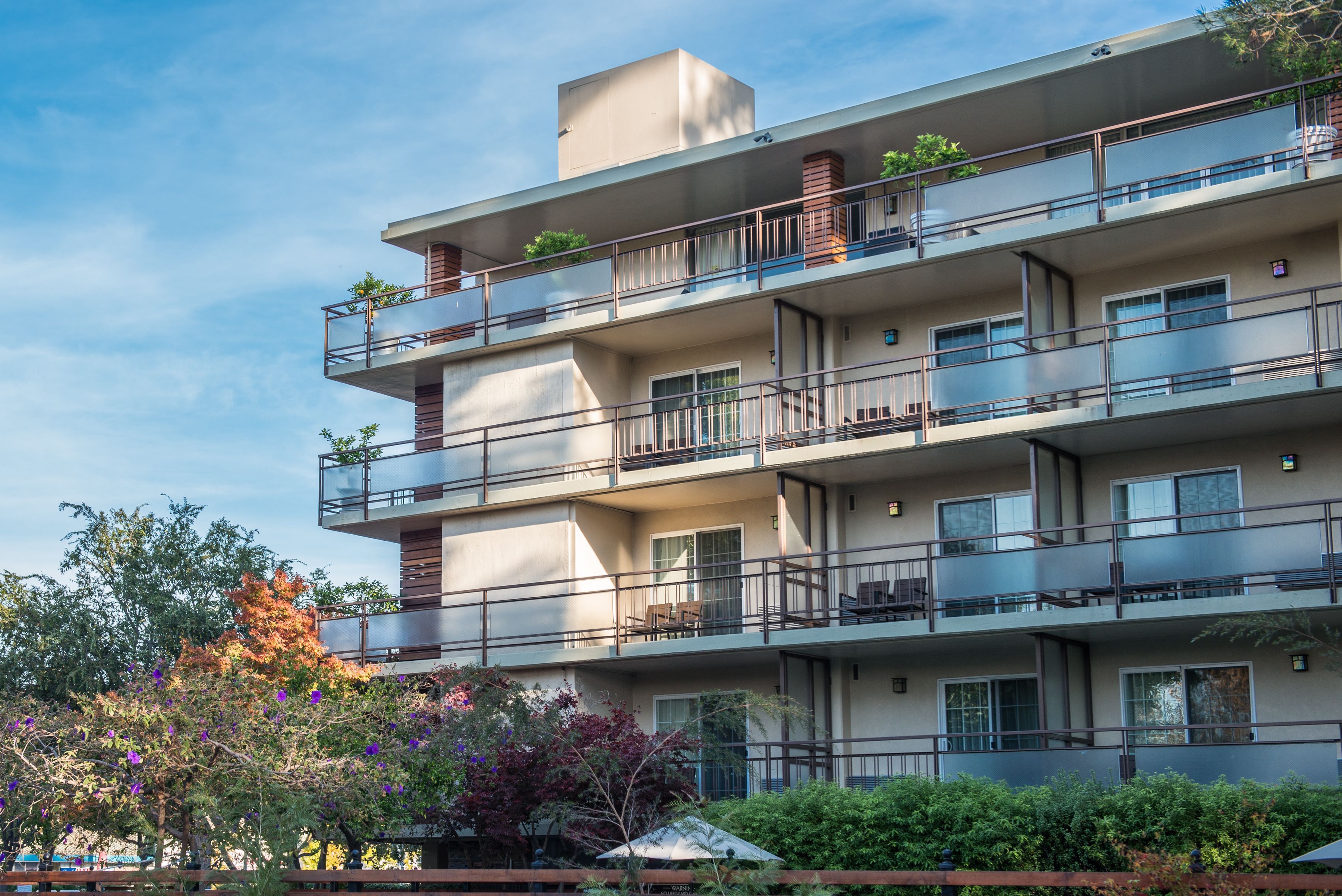 Un edificio residencial de varios pisos con balcones, ventanas y cielo despejado.