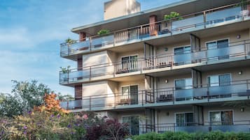 Un edificio residencial de varios pisos con balcones, ventanas y cielo despejado.