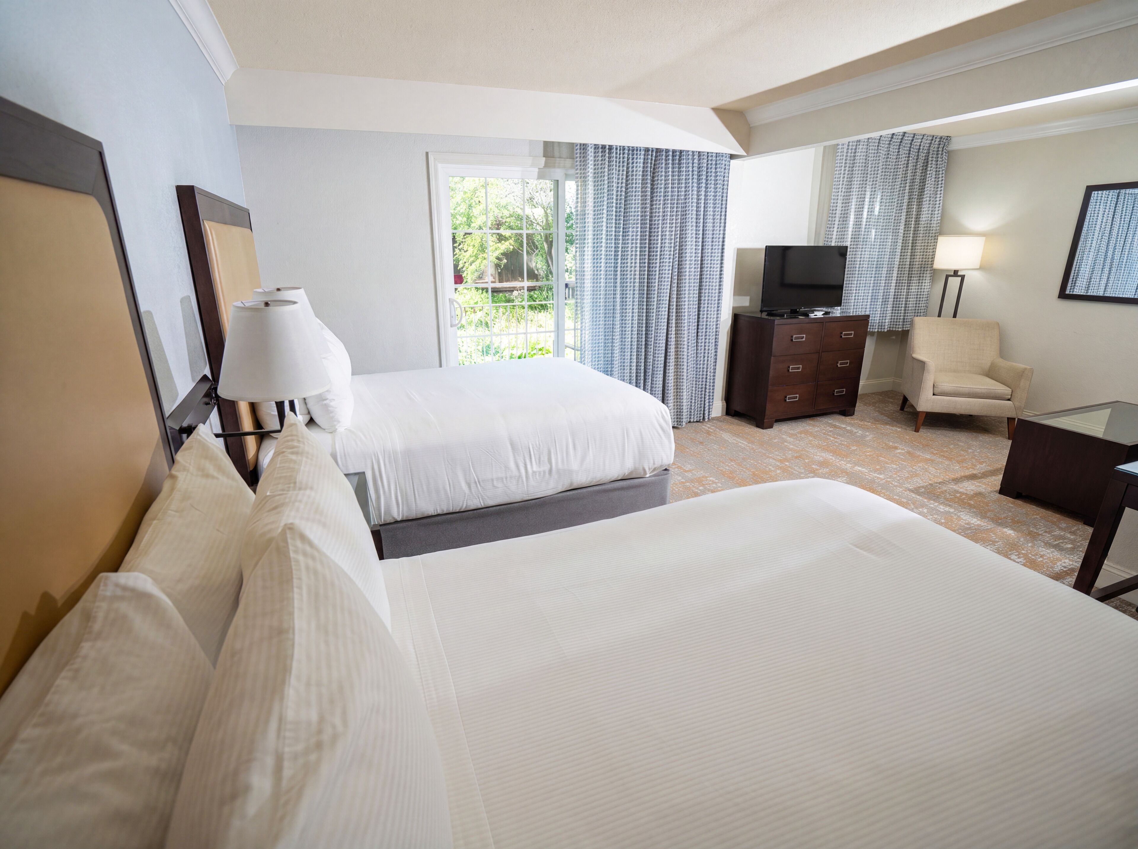 Una habitación de hotel con dos camas, televisión, una silla y escritorio.