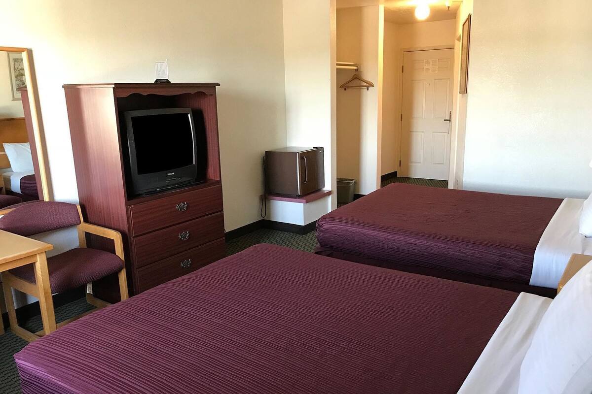 A hotel room with two beds, a TV, a desk, and a wardrobe.