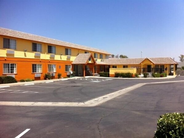 Um motel com fachada amarela e estacionamento.