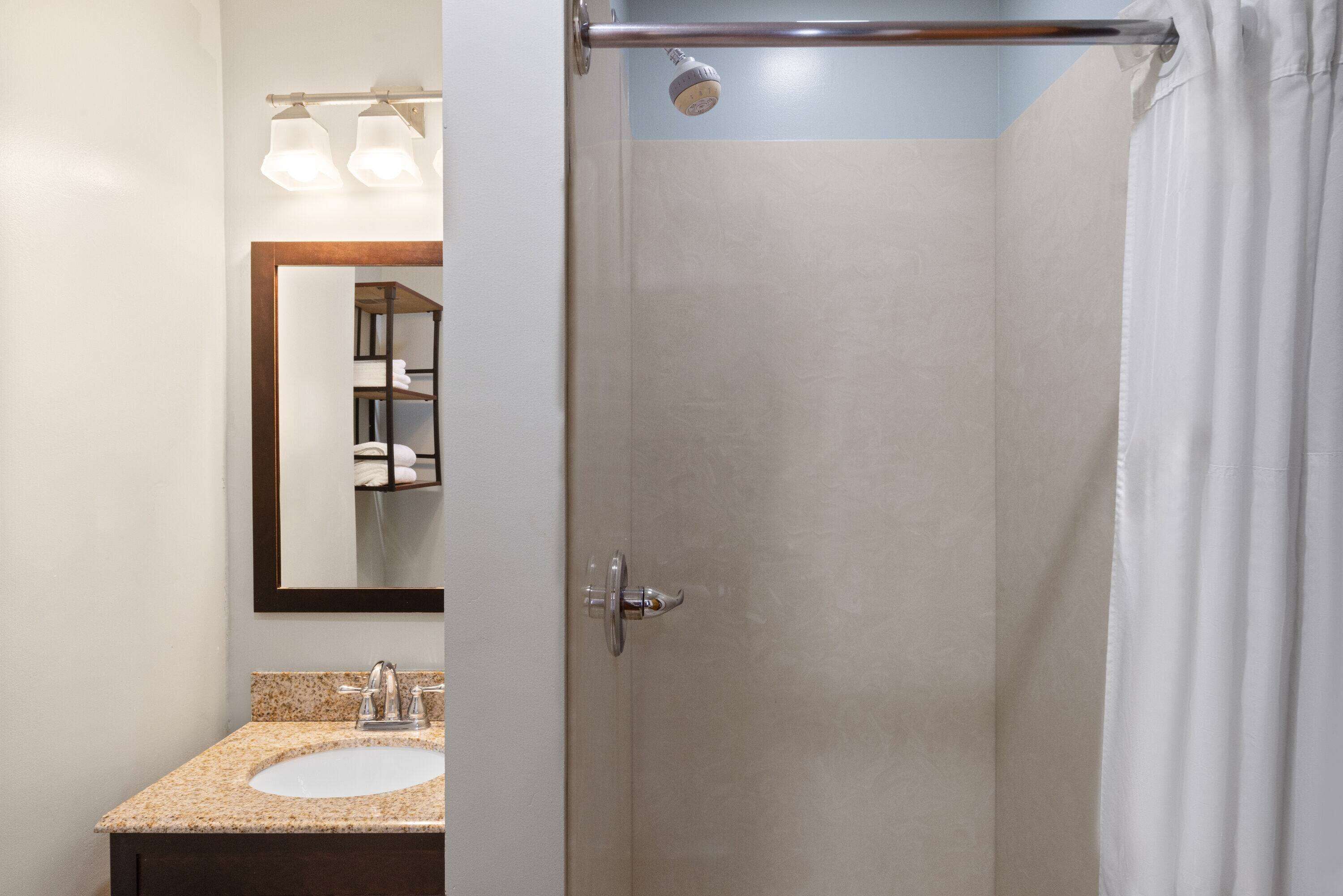 Een badkamer met een wastafel, spiegel en douche.