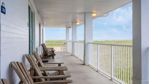 A covered porch with wooden chairs and a view of the beach. - Days Inn by Wyndham Kill Devil Hills Oceanfront - Wilbur (Kill Devil Hills)