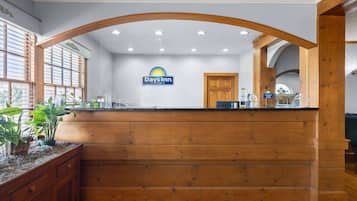 A reception area with a wooden counter, a sign for Days Inn, and a window with blinds.