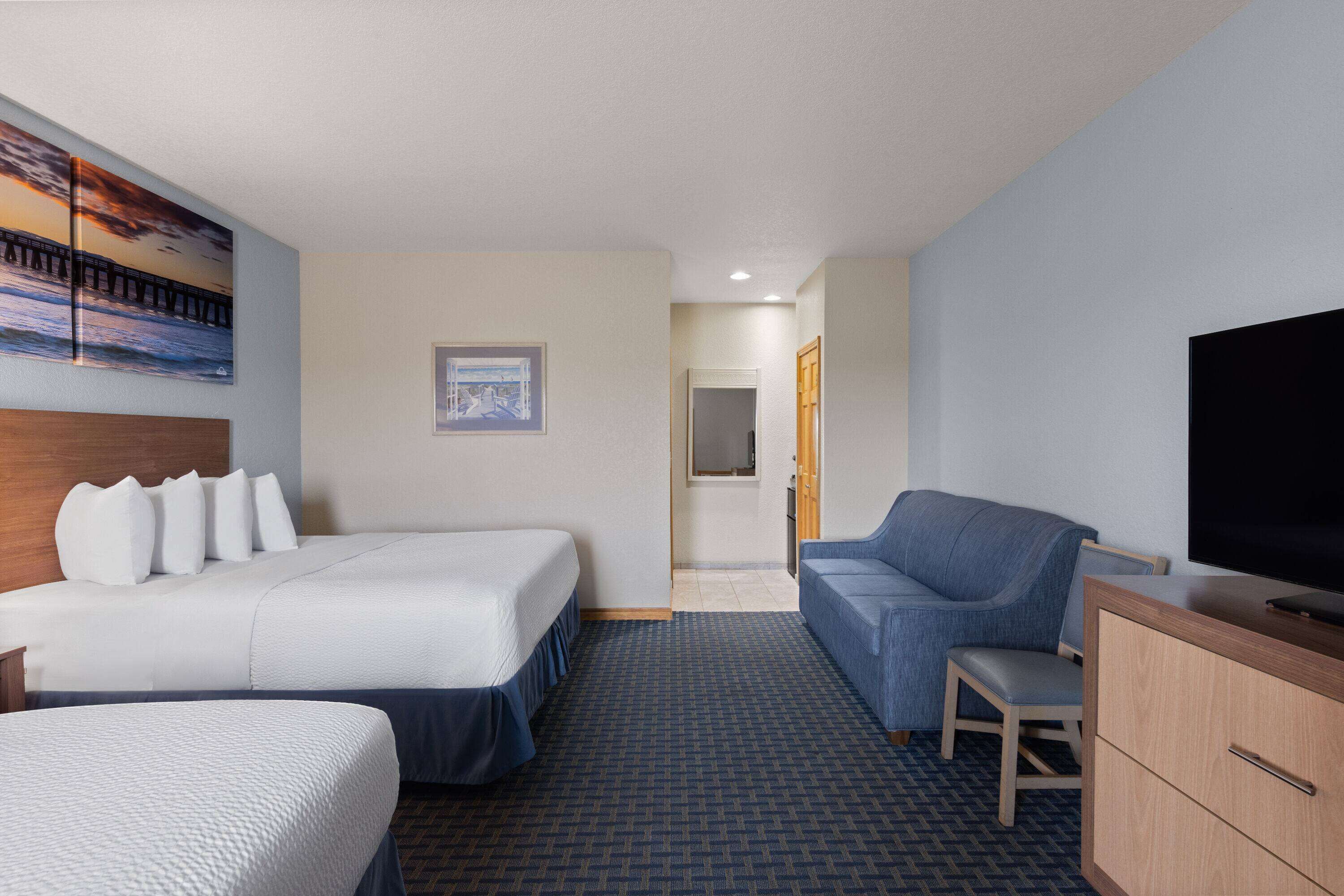 Een hotelkamer met twee bedden, een bank, een televisie en een klein bureau.