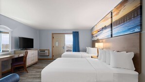 A hotel room with two beds, a desk, a TV, and a large window with a view of the outdoors. - Days Inn by Wyndham Kill Devil Hills Oceanfront - Wilbur (Kill Devil Hills)