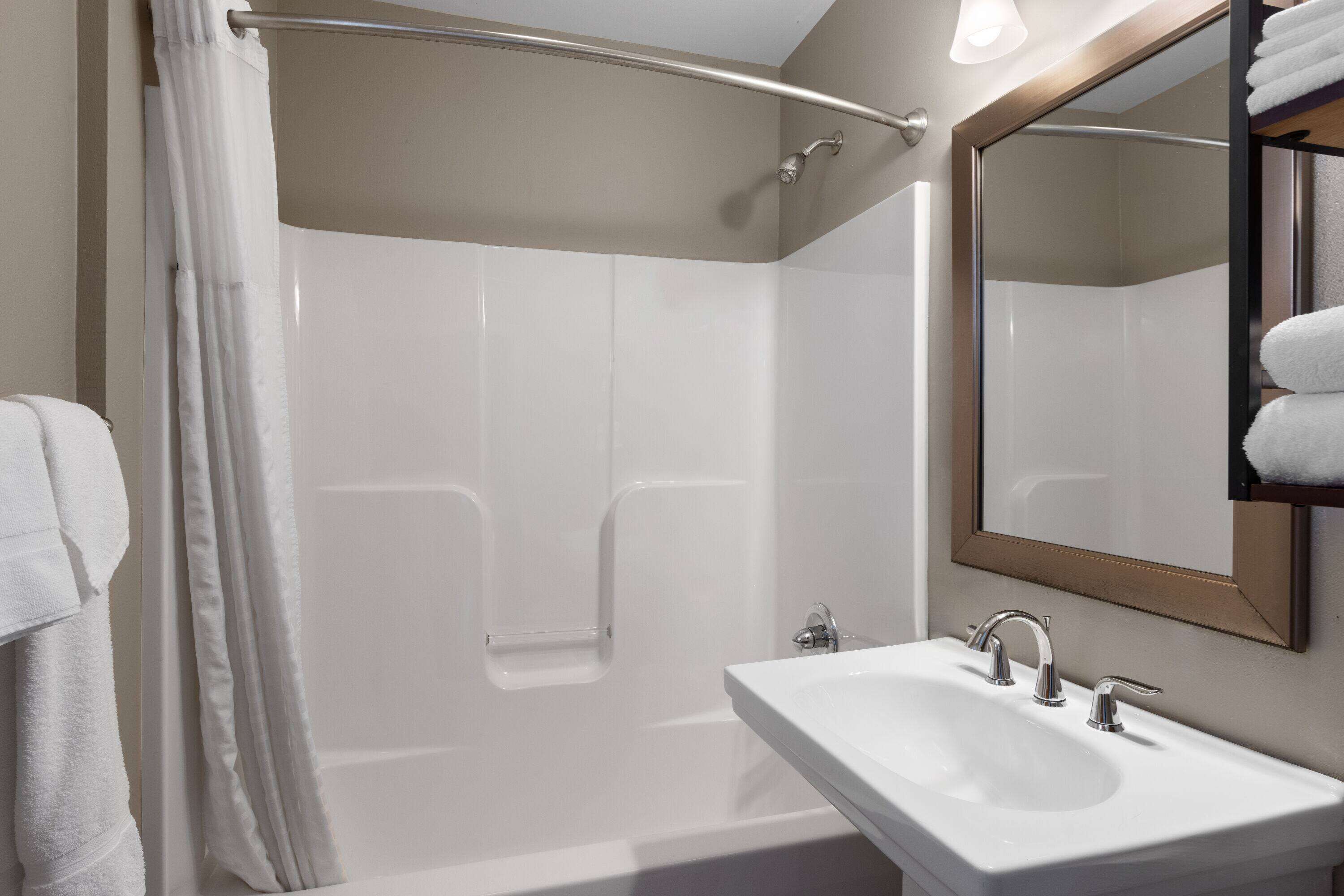 Un baño moderno con bañera, lavamanos y espejo.