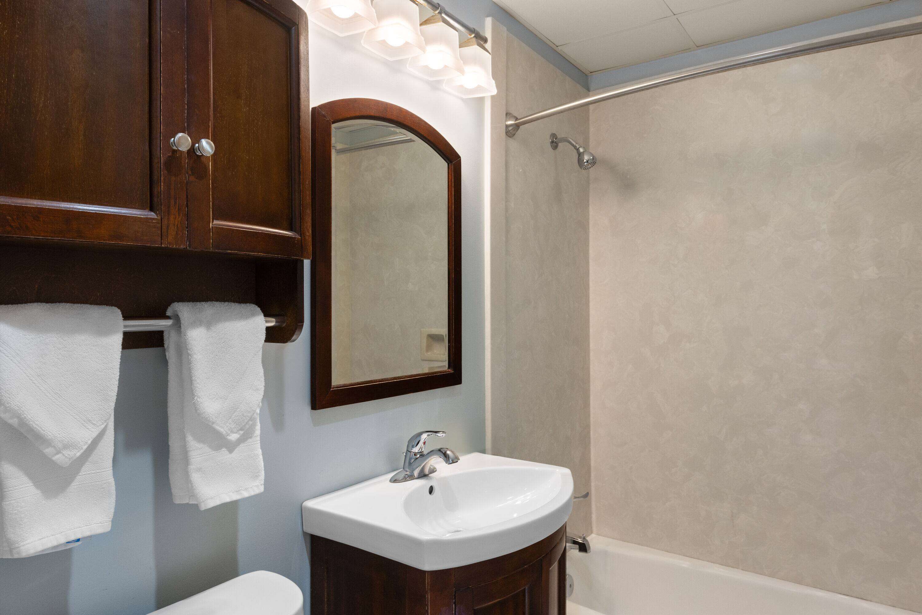 A bathroom with a white sink, a mirror, and a shower.