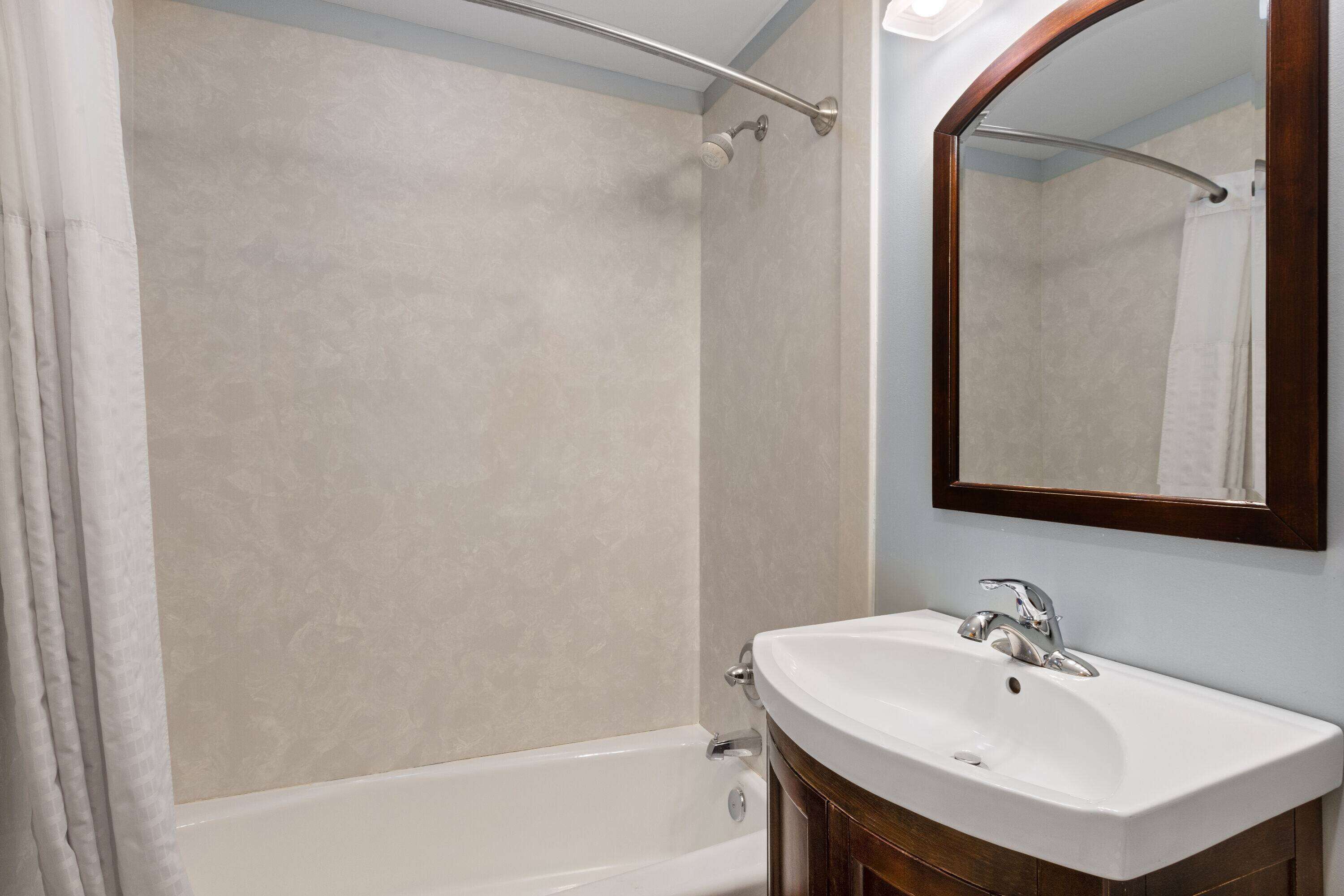 Un bagno con una vasca, un lavandino e uno specchio.