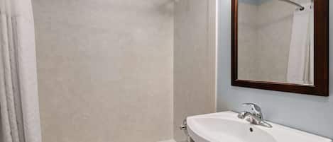 A bathroom with a bathtub, a sink, and a mirror.