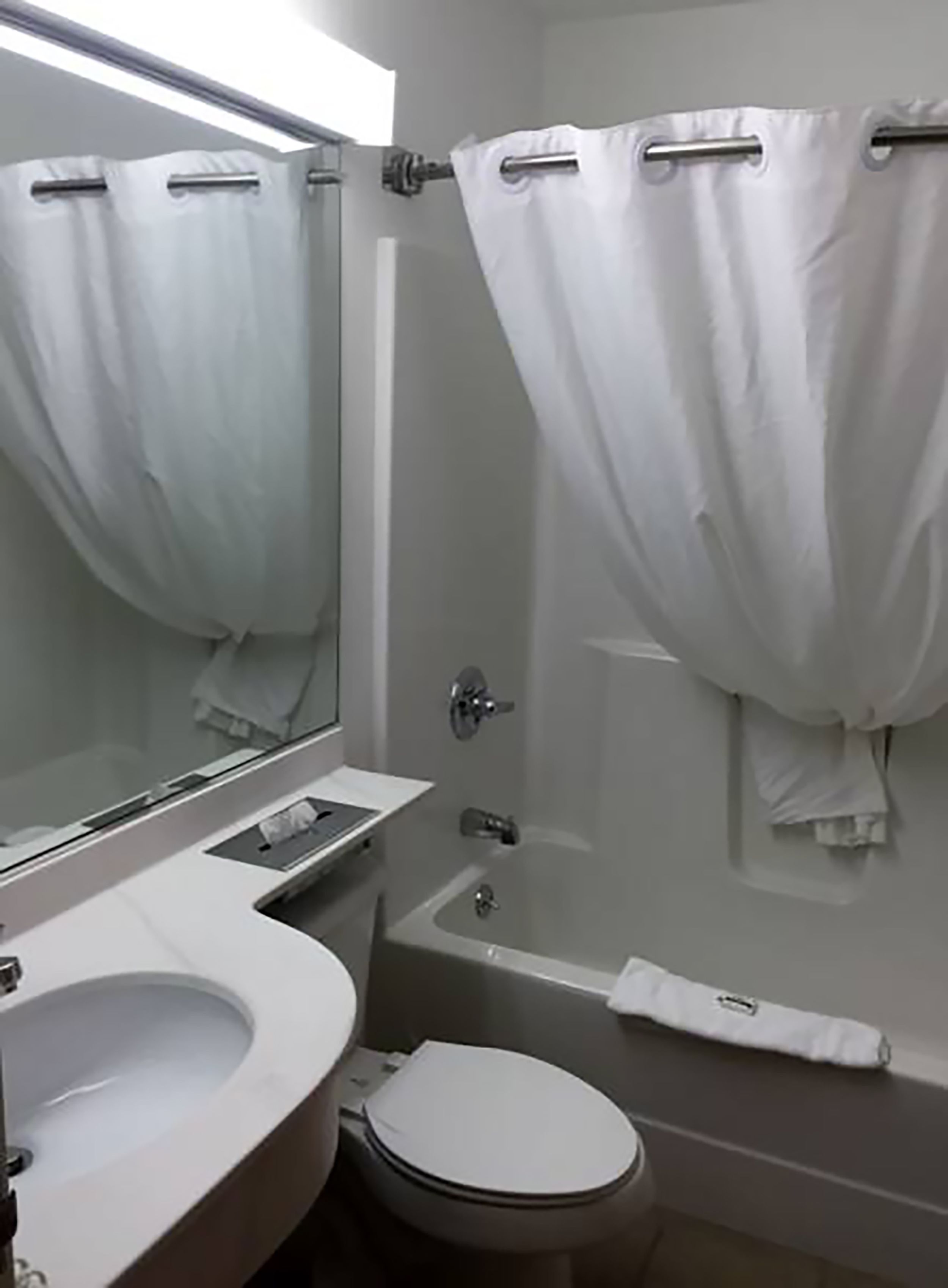 Une salle de bain avec un lavabo, des toilettes et une baignoire, le tout de couleur blanche.