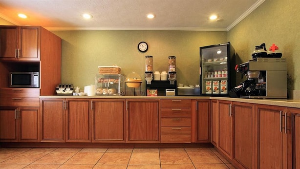 A kitchen with wooden cabinets, a microwave, a coffee machine, and a refrigerator. - Travelodge by Wyndham Beckley (Beckley)