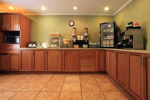 Una cocina con armarios de madera, microondas, cafetera y refrigerador.