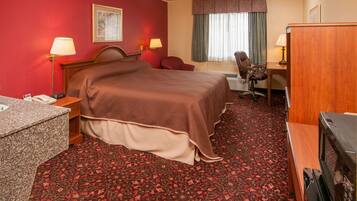 A hotel room with a bed, desk, chair, and a TV.