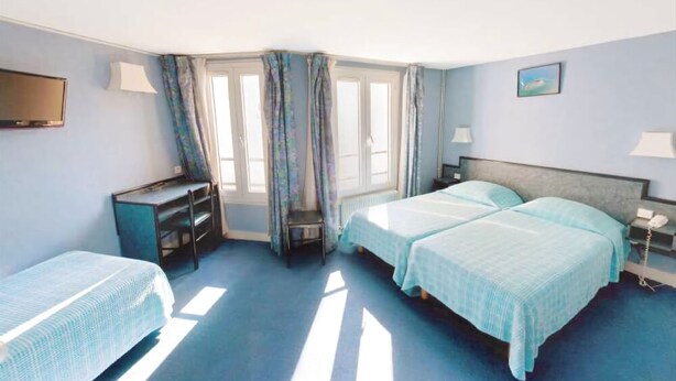 A hotel room with two beds, a desk, a chair, a TV, and a window with curtains. - Hôtel Royal Bergère (Paris)