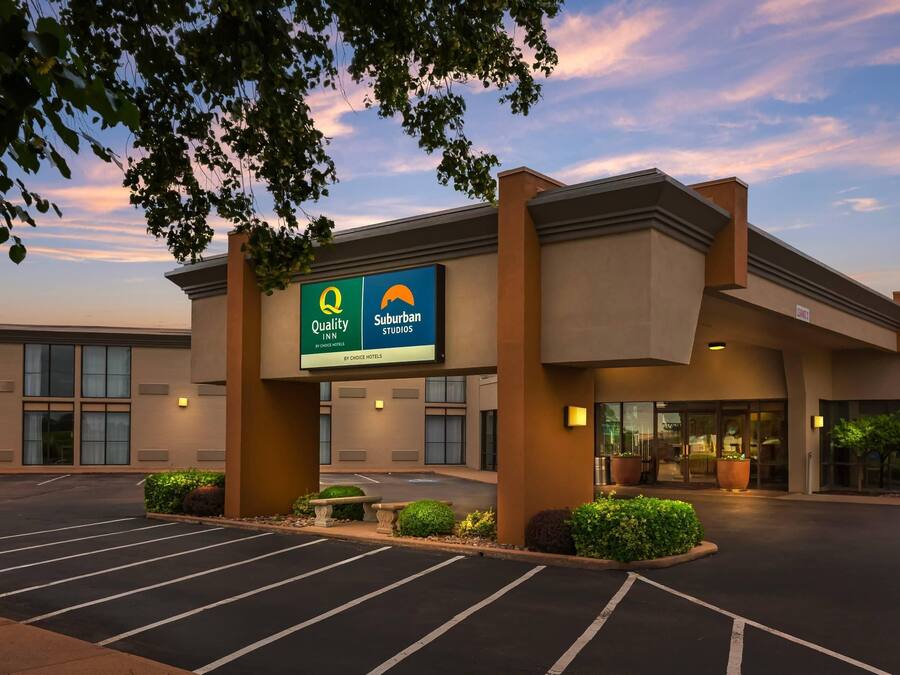 A hotel with a sign for 'Quality Suburban Studios by Choice Hotels' and a parking lot.