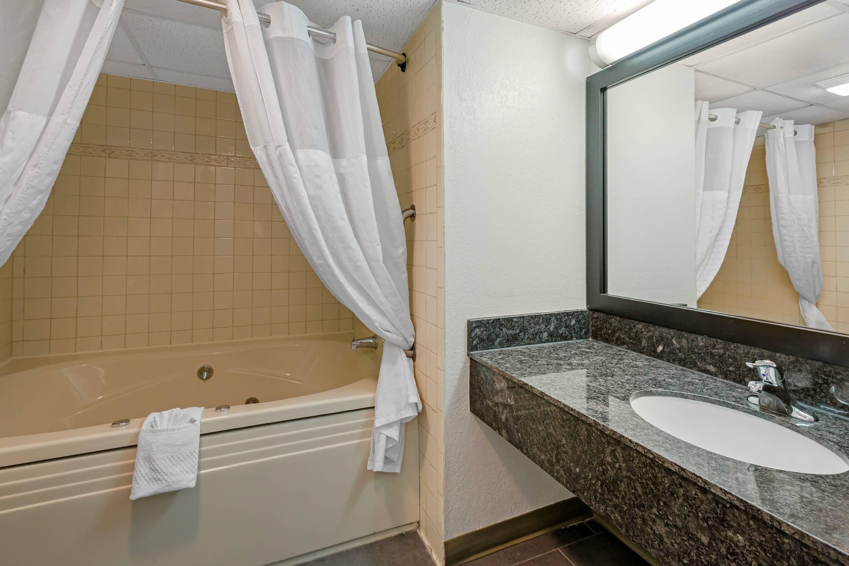 A bathroom with a bathtub, a sink, and a mirror.