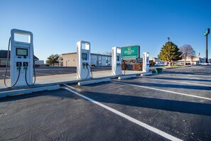 A parking lot with electric vehicle charging stations, a Quality Inn Conference Center sign, and a building in the background. - Quality Inn and Conference Center I-80 Grand Island (Grand Island)