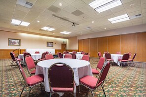 Una sala de conferencias con mesas redondas, sillas rojas y suelo alfombrado.