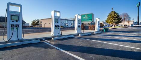 Un estacionamiento con estaciones de carga para vehículos eléctricos, un cartel del Quality Inn Conference Center y un edificio al fondo.