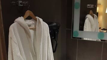Un bagno con un lavandino bianco, uno specchio e un accappatoio appeso a un appendiabiti.