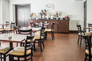 A restaurant with wooden tables and chairs, a coffee bar with various appliances, and a sign on the wall. - Sleep Inn Beaver - Beckley (Beaver)