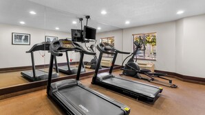 Une salle de sport équipée de tapis de course, d’un vélo d’appartement et d’un rameur.