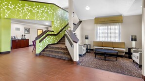 Un hall d’hôtel avec un escalier, un canapé, une table basse et un coin repas.