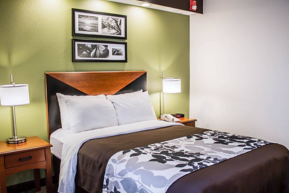 A hotel room with a bed, two bedside lamps, a nightstand, and a wall-mounted telephone.