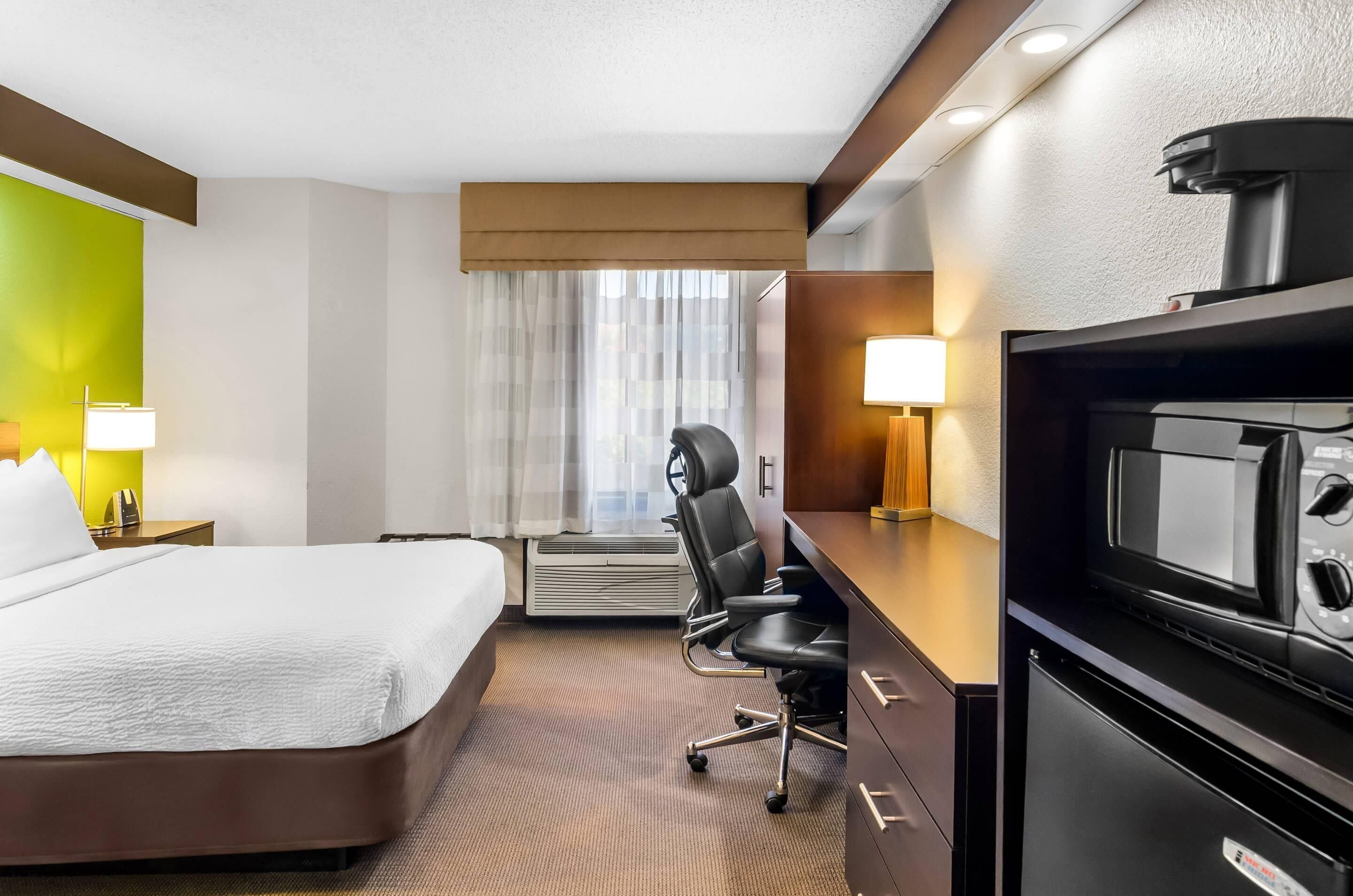 Una habitación de hotel con cama, escritorio, microondas y cafetera.