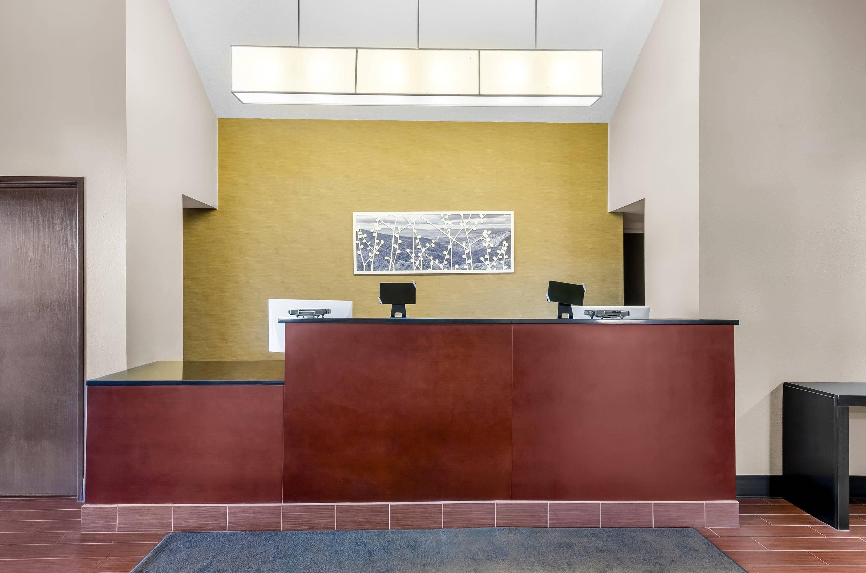 A reception desk with a modern design, a yellow accent wall, and a framed artwork above it.