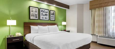 A hotel room with a large bed, green walls, and framed pictures on the wall.