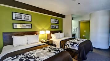 Una habitación de hotel con dos camas, una mesita de noche con lámpara y cuadros en la pared.