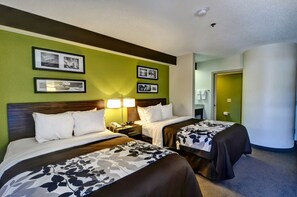 A hotel room with two beds, a nightstand with a lamp, and framed pictures on the wall.