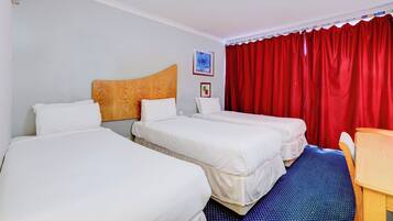 Habitación de hotel con dos camas, cabecera de madera, escritorio y cortina roja.