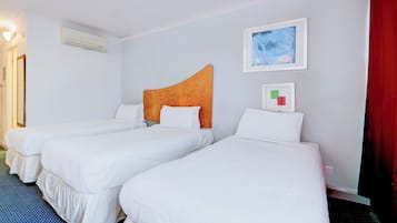 Ein Hotelzimmer mit drei Einzelbetten, einem großen Fenster und einem roten Vorhang.